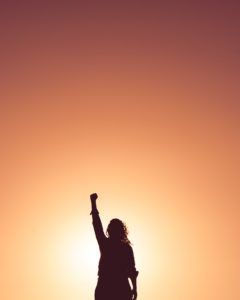 Silhouette of woman holding one fist in the air