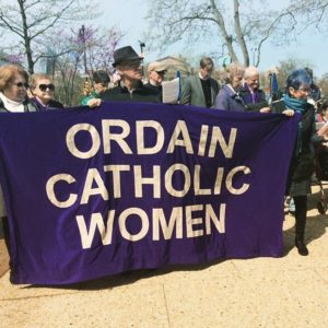 Group of people holding a purple banner with the words "Ordain Catholic Women." 