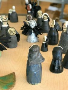 A table with a series of small ceramic figurines of nuns in black habits.
